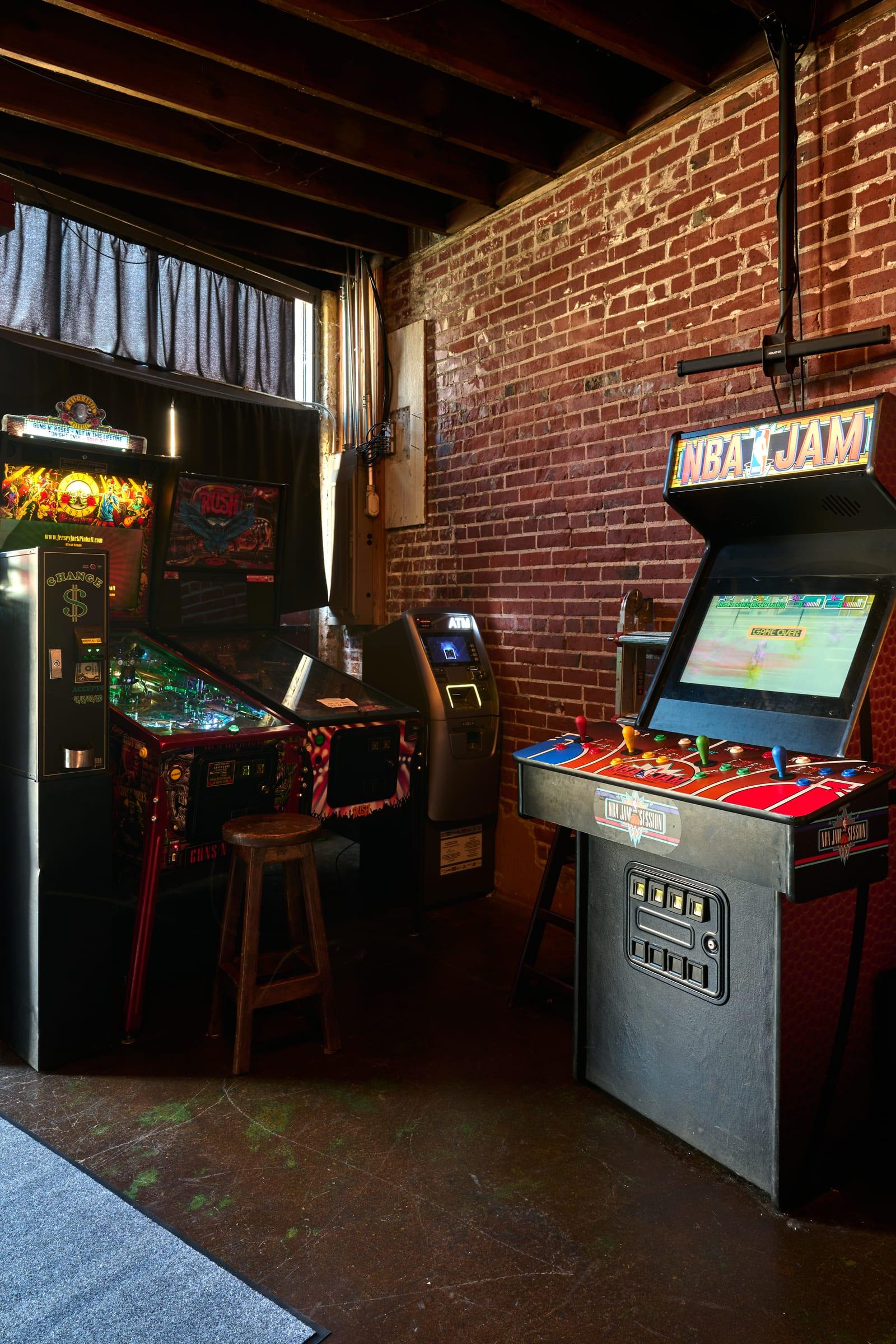 Real pinball at McFiler's Chehalis: Stern's Rush and Guns N' Roses pinball machines next to an NBA Jam arcade cabinet, exposed brick wall