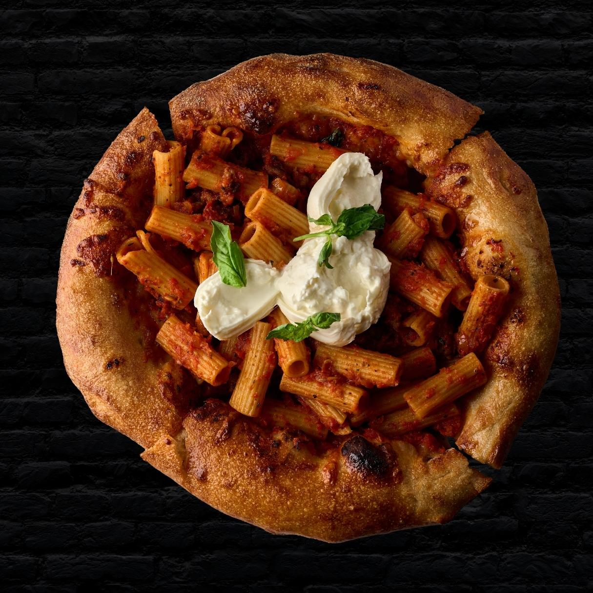 Rigatoni bolognese served on a cheese-pizza bowl